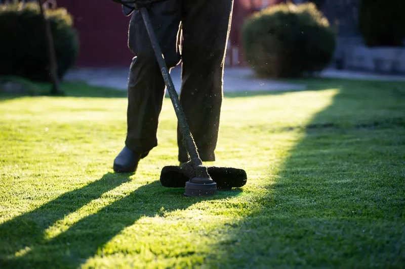 Perfectly maintained artificial turf lawn with trimmed hedges and gravel edging in Southern California