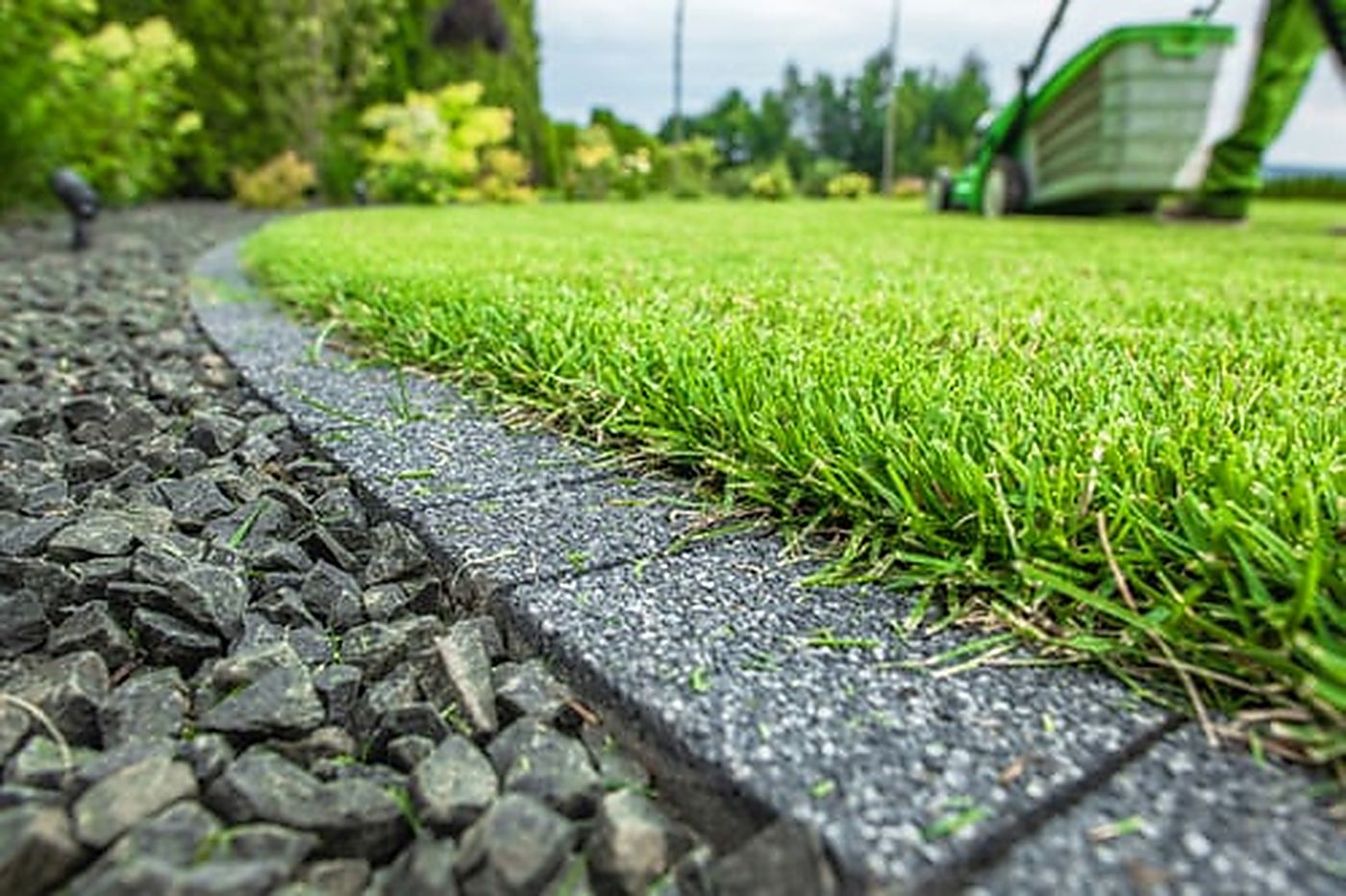 Clean, well-maintained artificial turf edge running alongside a decorative gravel border