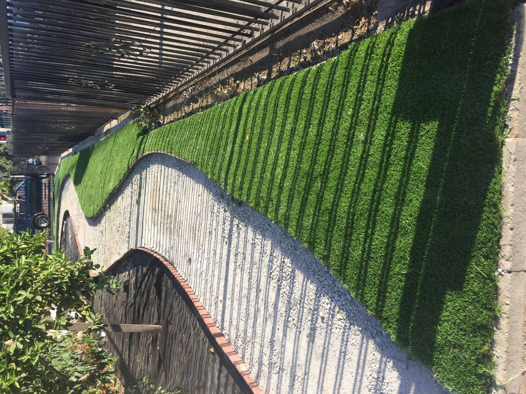 Curved artificial turf strip alongside a paver walkway on a 3RS Landscaping project